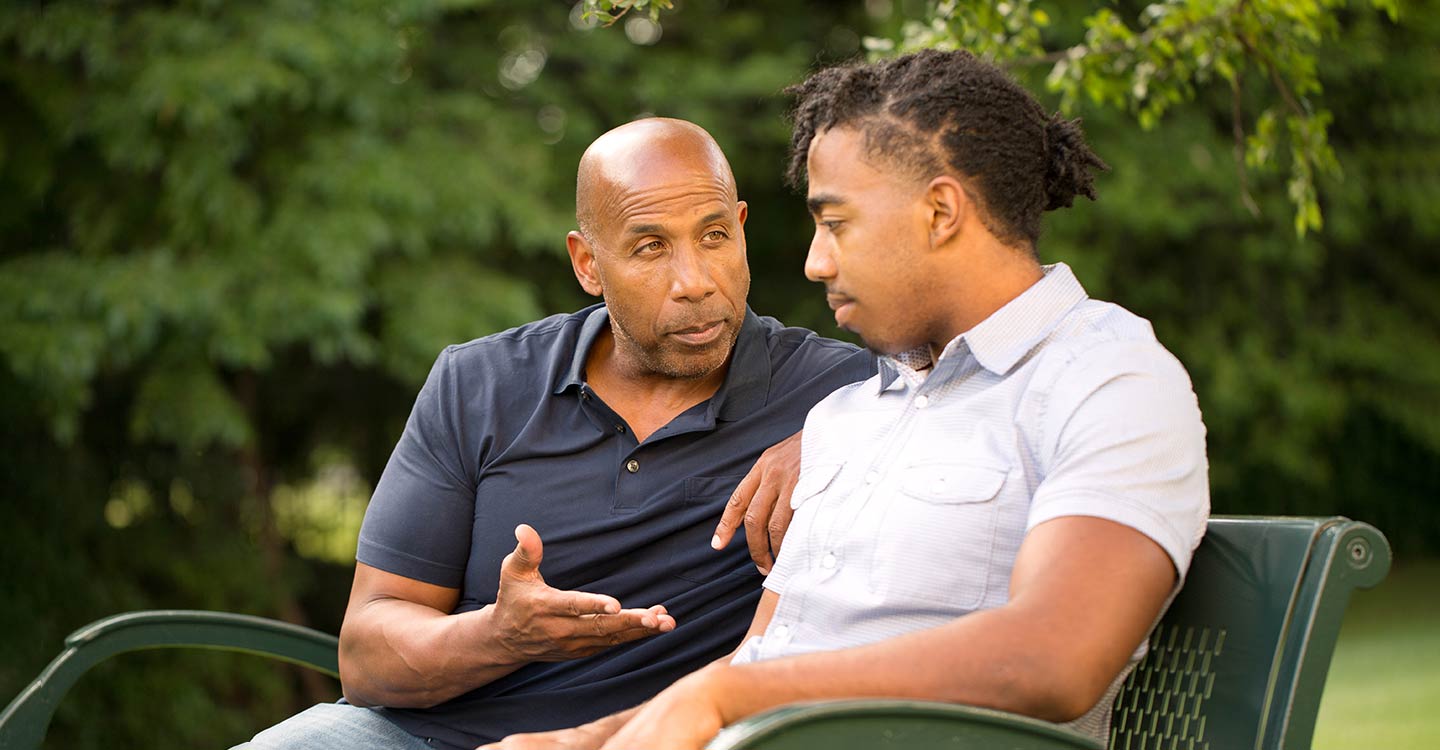 father gives son advice on park bench